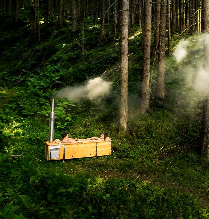 Paar in Gartenbadewanne mit Holzofen