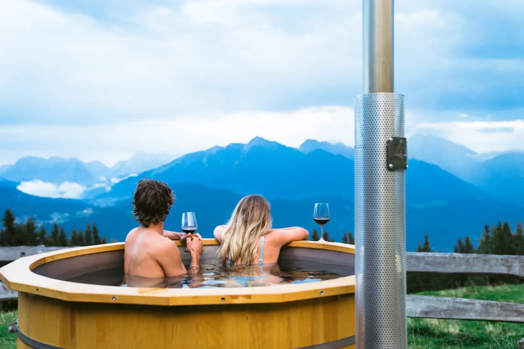 Paar sitzt im Badezuber mit Blick auf ein Bergpanorama