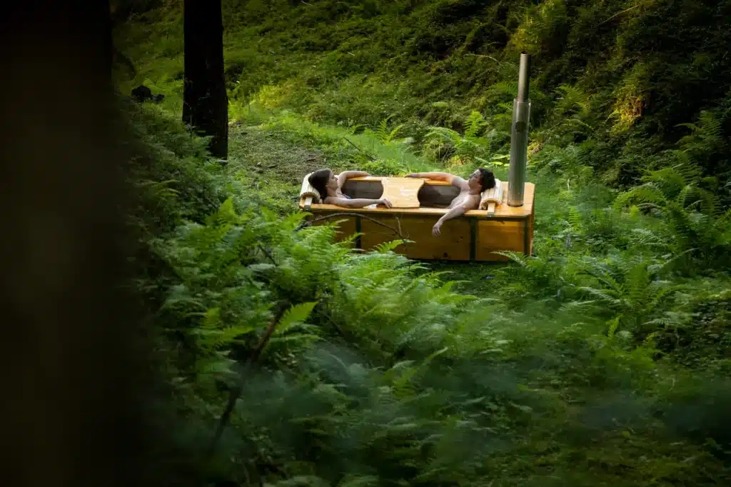 Outdoor-Badewanne von Feuerwasser mit Paar im Wald