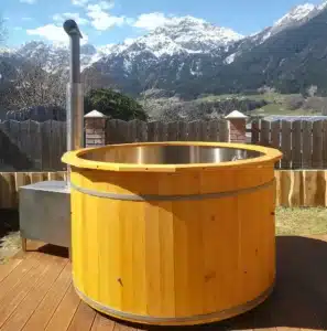 Feuerwasser Badefass mit V4A-Edelstahlwanne und Holzofen im Garten mit Bergpanorama