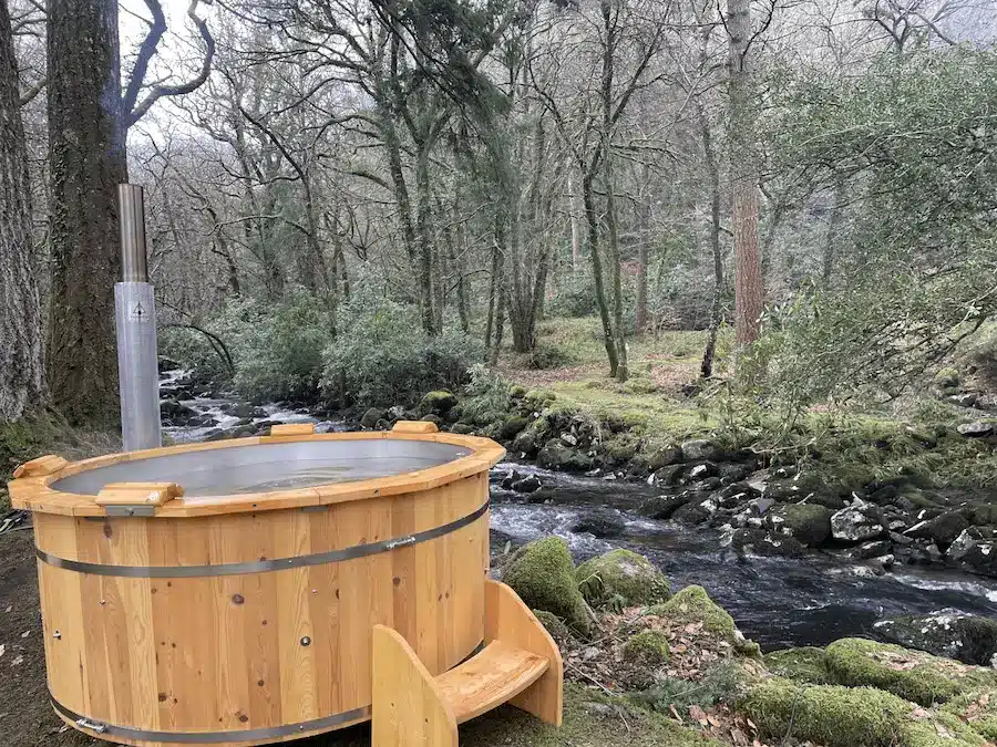 Holzbadefass von Feuerwasser mit Holzofen direkt am wilden Fluss im Wald