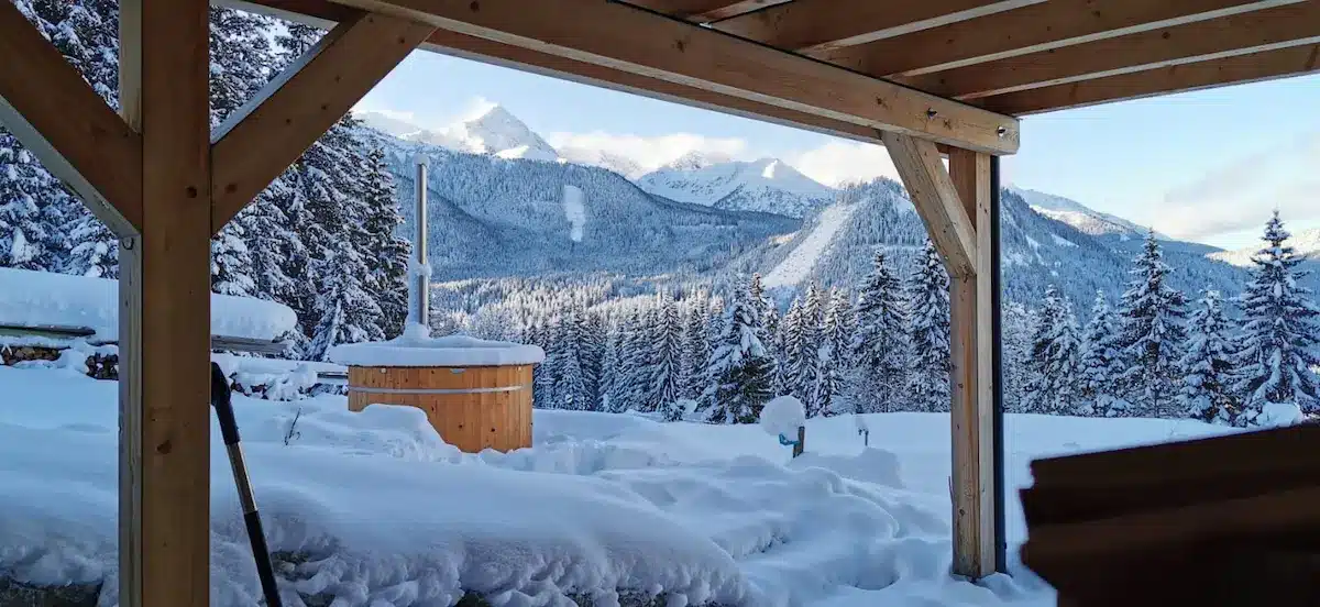 Holzbadefass von Feuerwasser mit Holzofen im tief verschneiten Alpenpanorama der Hohen Tauern