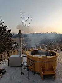 Holzbefeuerter Feuerwasser Hot Tub im Winter bei Sonnenuntergang mit Außenofen