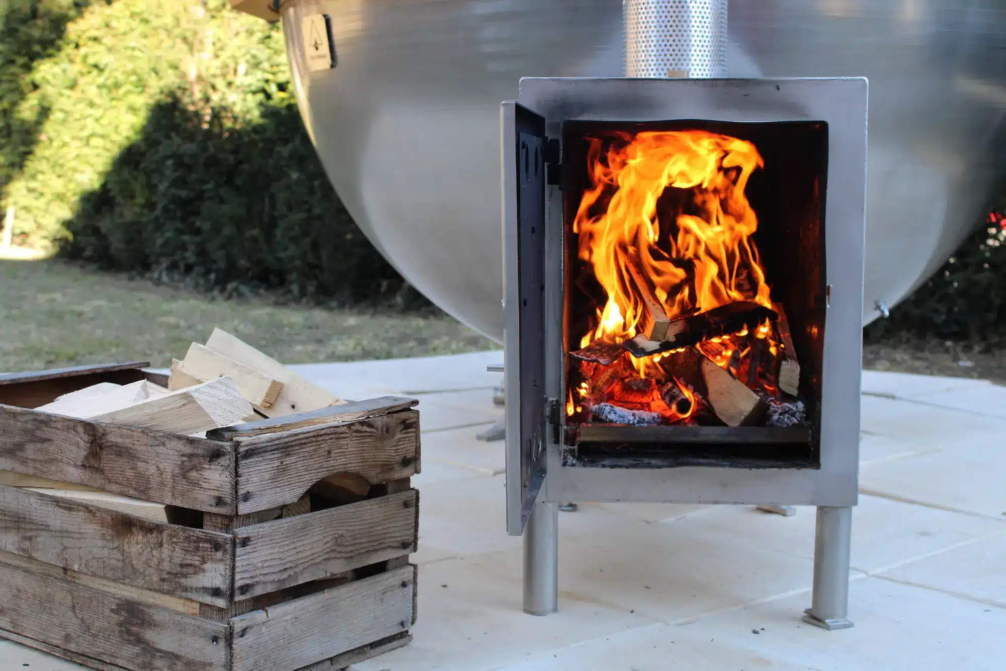 Utomhusbadtunna från Feuerwasser med brinnande eld och trälåda bredvid
