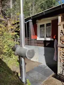 Holzbefeuerte Edelstahl-Gartendusche von Feuerwasser vor einer Hütte, Outdoor-Dusche mit laufendem Wasser im Wald
