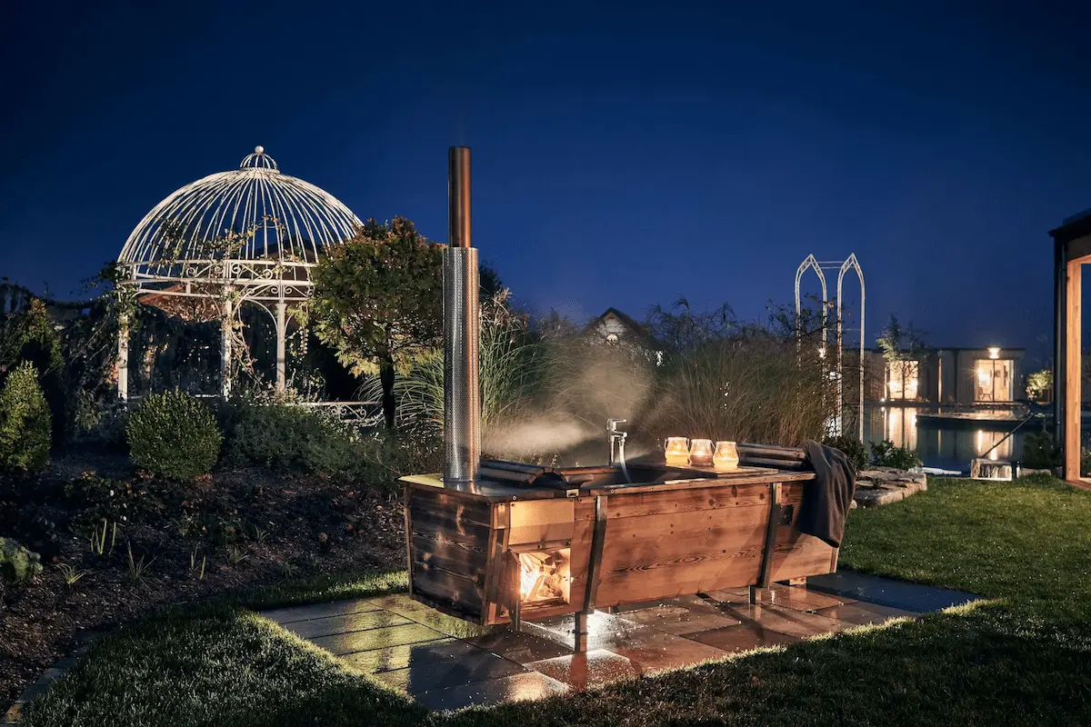 Beheizte Outdoor-Badewanne von Feuerwasser bei den Kittenberger Chalets im nächtlichen Gartenambiente
