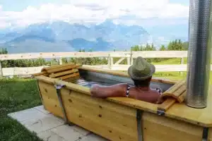 Outdoor-Badewanne aus V4A-Edelstahl mit Kiefernholz von Feuerwasser vor Bergpanorama mit Frau