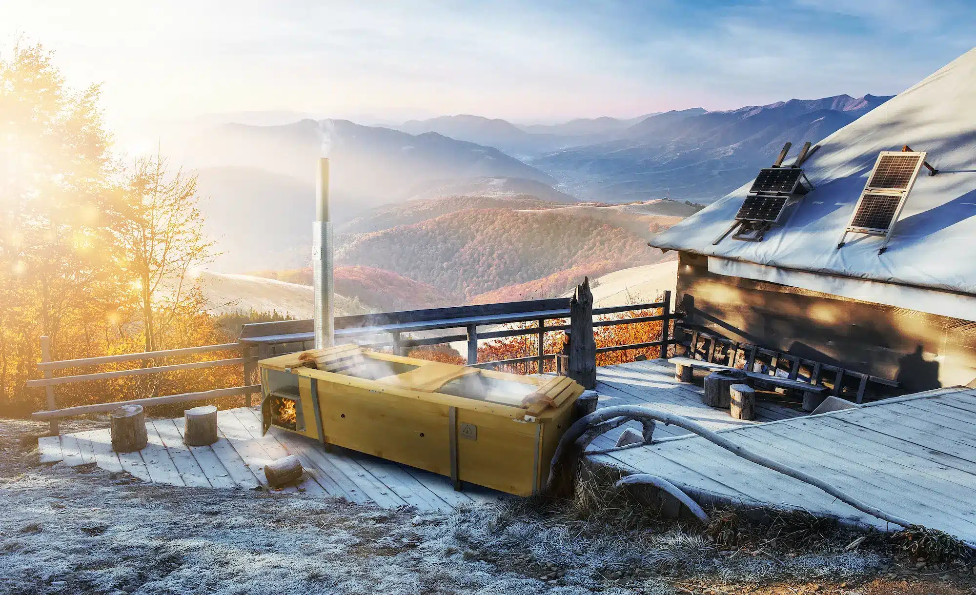 Outdoor-Badewanne mit Holzofen vor Bergpanorama im Herbst und Winter von Feuerwasser