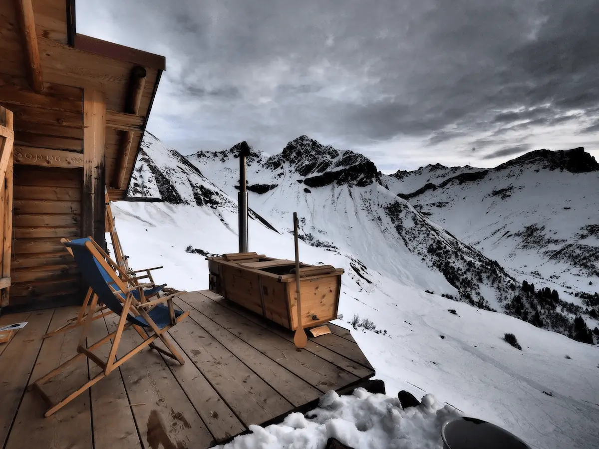 Beheizbare Outdoor-Badewanne von Feuerwasser auf Berghütte im verschneiten Hochgebirge