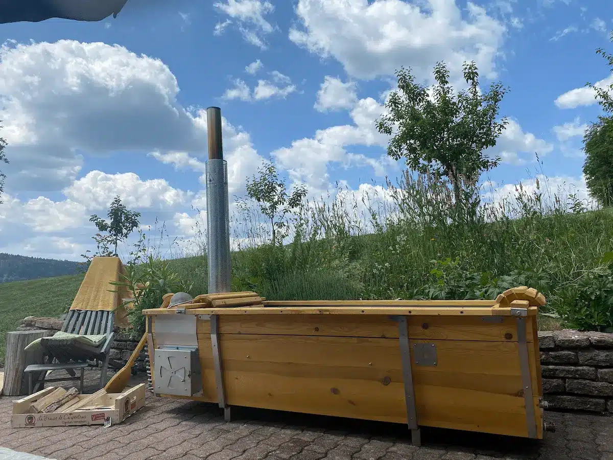 Outdoor-Badewanne aus Edelstahl und Kieferholz am sonnigen Landhang