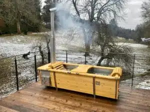 Outdoor-Badewanne von Feuerwasser aus V4A-Edelstahl mit Kiefernholz auf winterlicher Terrasse