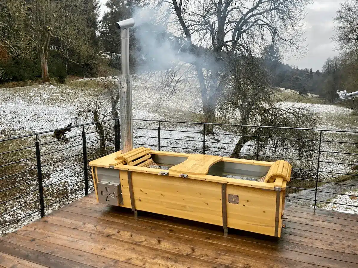 Outdoor-Badewanne von Feuerwasser aus V4A-Edelstahl mit Kiefernholz auf winterlicher Terrasse