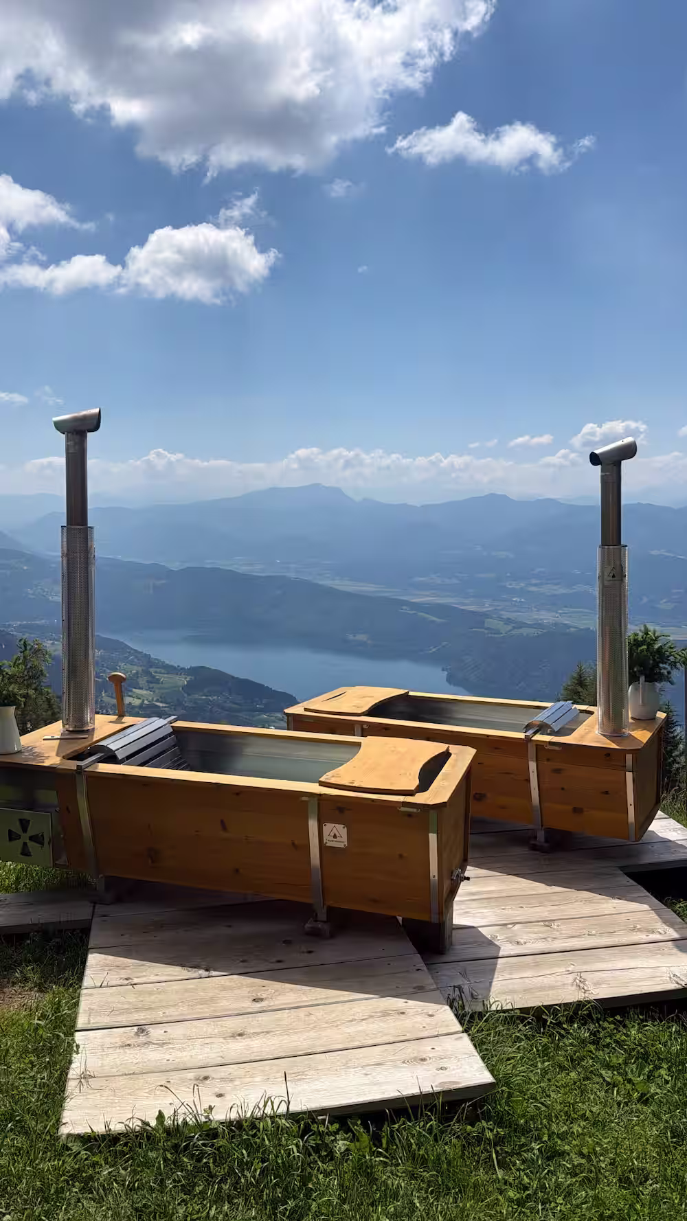 Two outdoor bathtubs with wood stoves overlooking a lake and mountains, customer photo