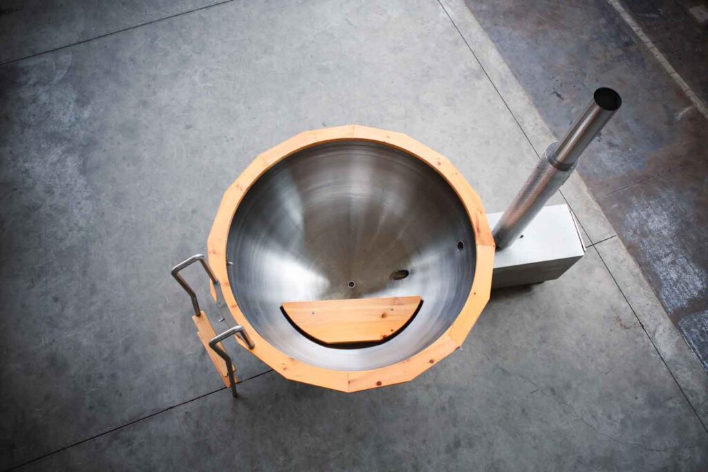 Stainless steel cup of firewater from above with benches made of solid pine wood